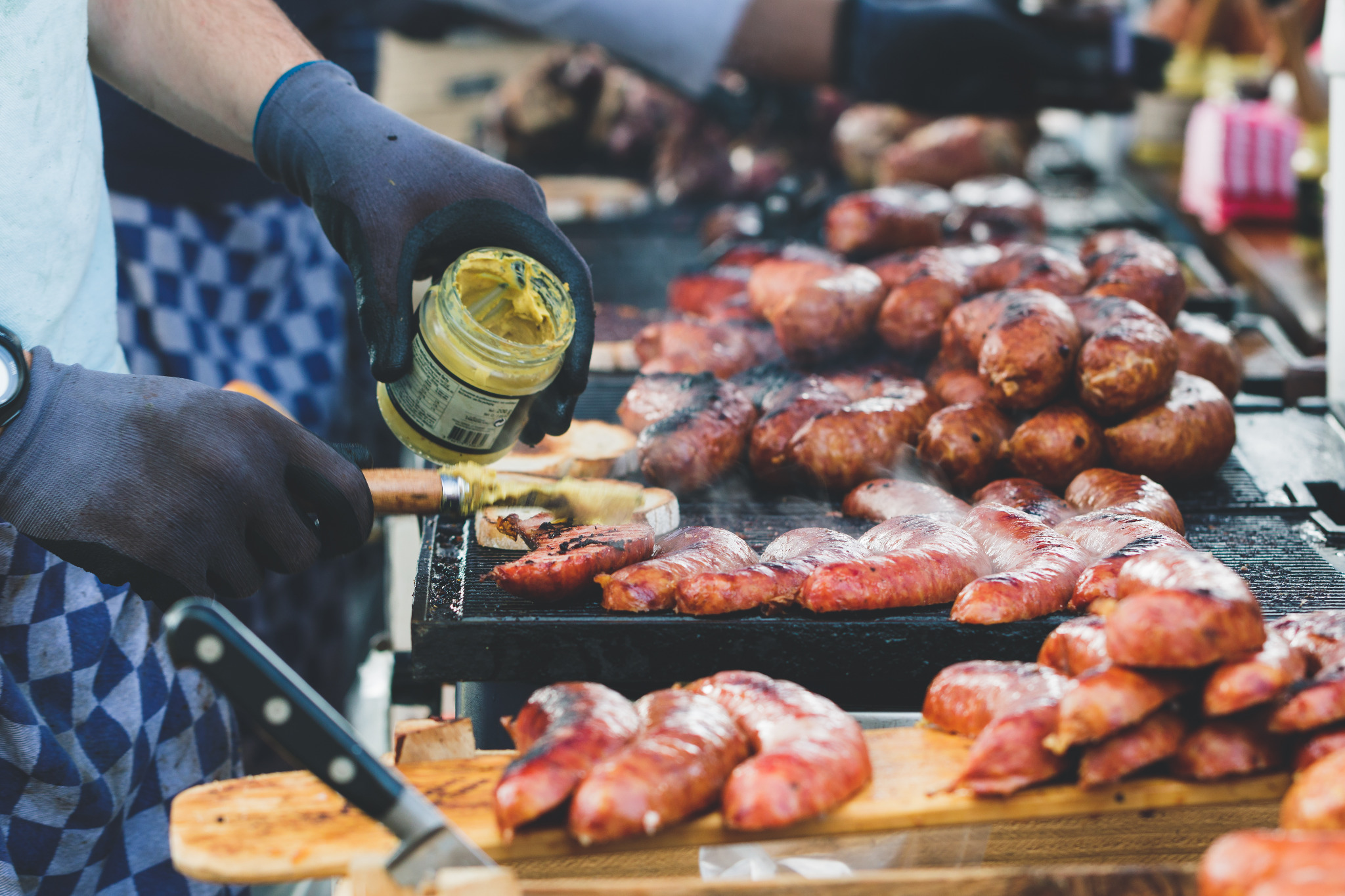 Cook preparing grilled sausages with mustard